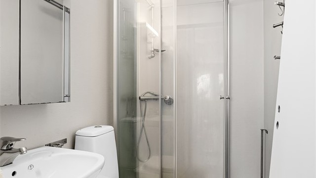 Badet er utstyrt med dusjkabinett, servant og toalett