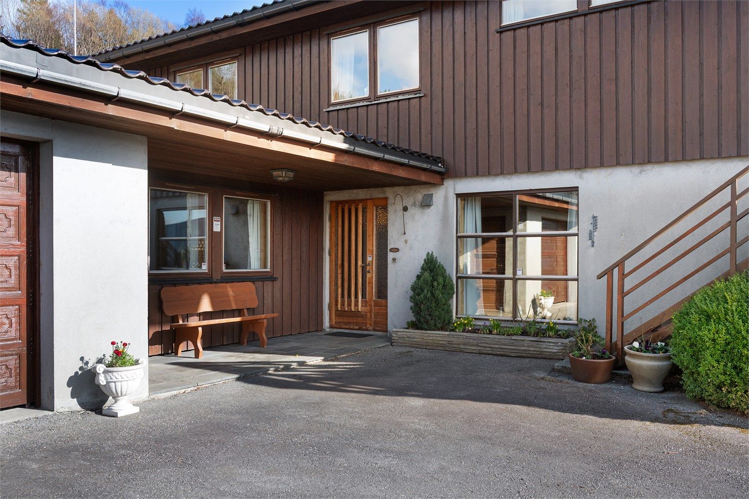 Overbygget inngangsparti i underetasjen med skiferheller mellom dør og garasje