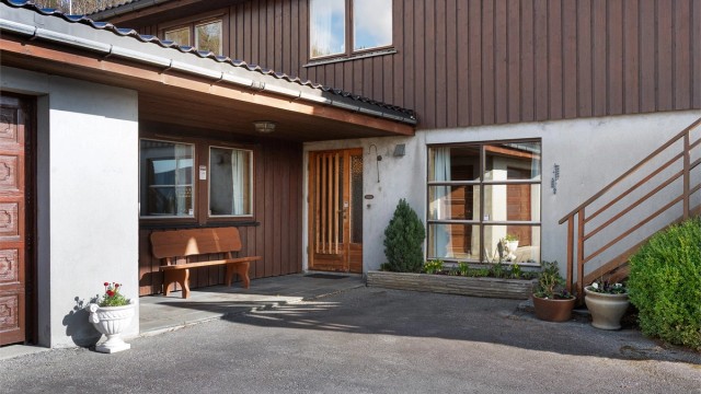 Overbygget inngangsparti i underetasjen med skiferheller mellom dør og garasje