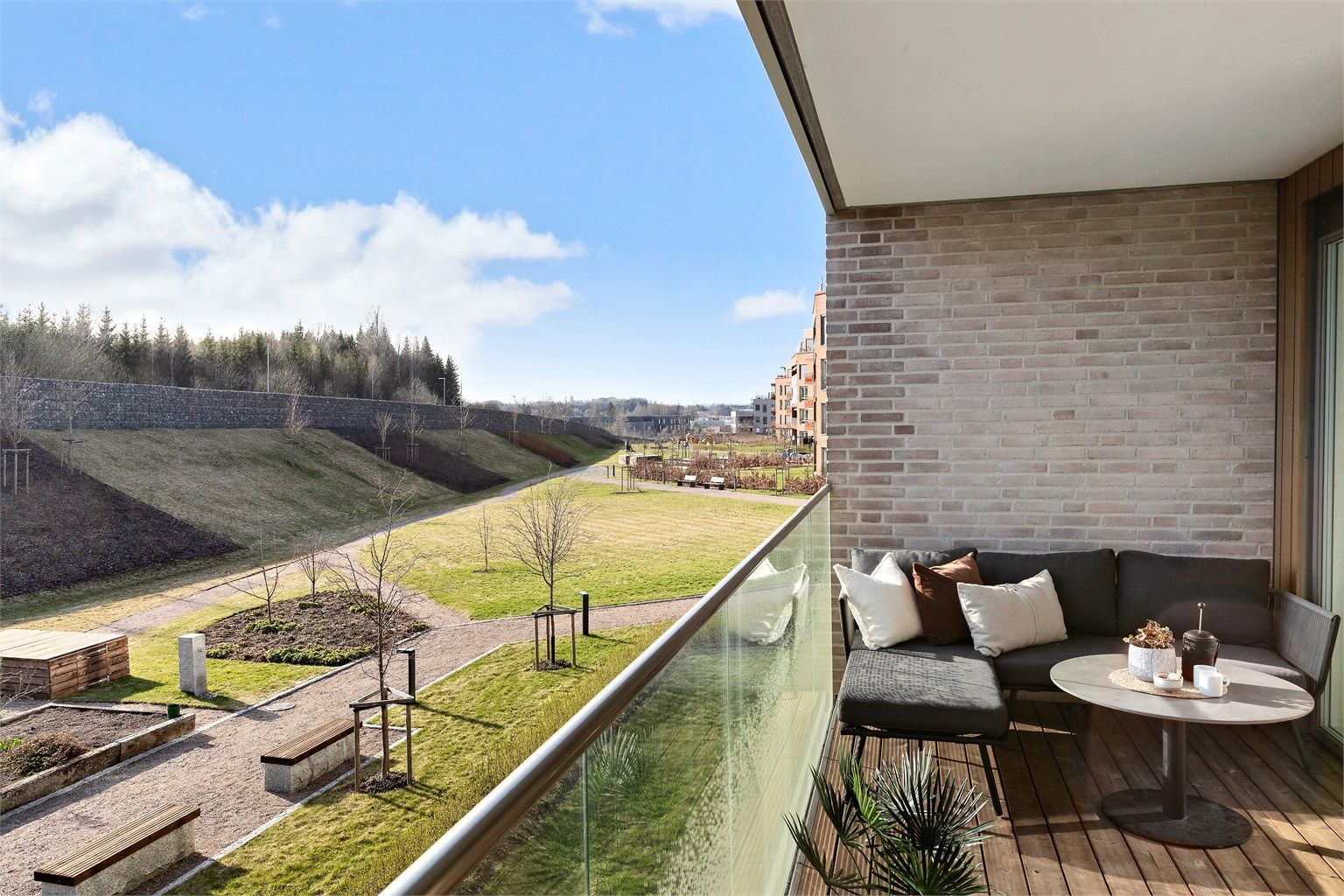 Balkongen er belagt med terrassebord og har rekkverk i metall og glass.