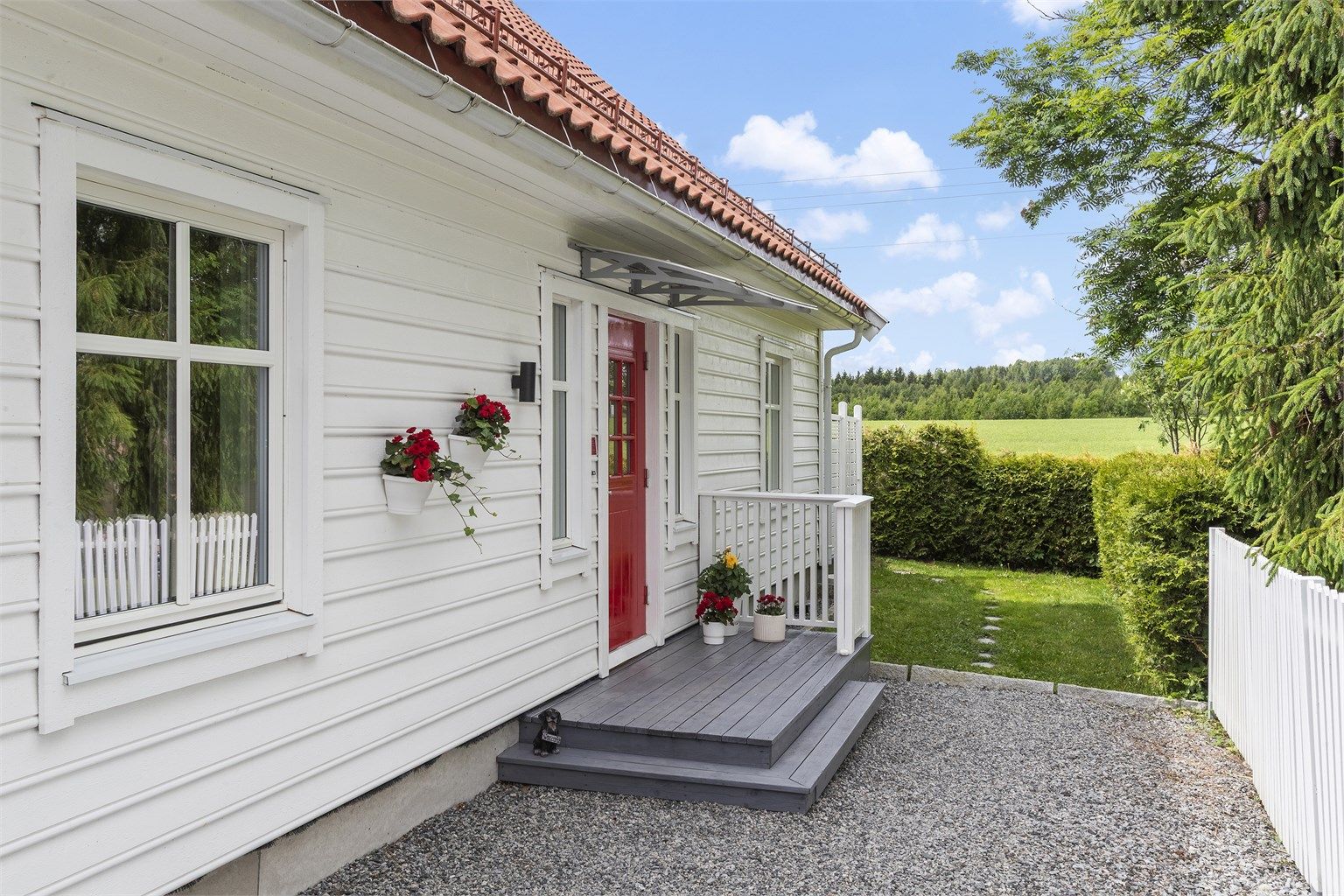 Tomten er pent opparbeidet med plen, hekk og en stor terrasseplatting. Gårdsplassen er gruset. 