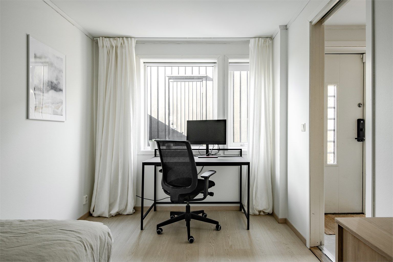 Rommet har plass til både seng og en praktisk arbeidsplass ved vinduet.