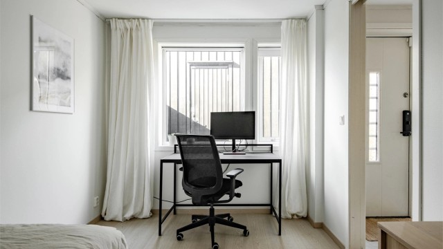Rommet har plass til både seng og en praktisk arbeidsplass ved vinduet.