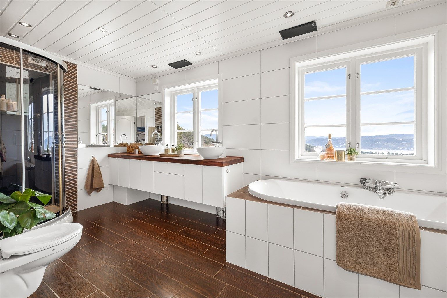 Det flislagte badet har varme i gulvet og er utstyrt med både innebygget badekar og dusjkabinett. Innredningen er fra KVIK.