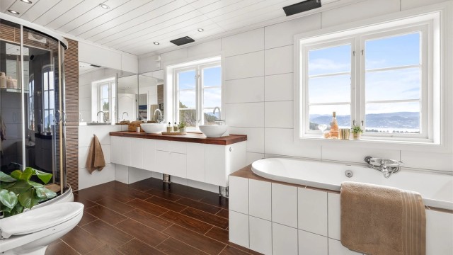 Det flislagte badet har varme i gulvet og er utstyrt med både innebygget badekar og dusjkabinett. Innredningen er fra KVIK.