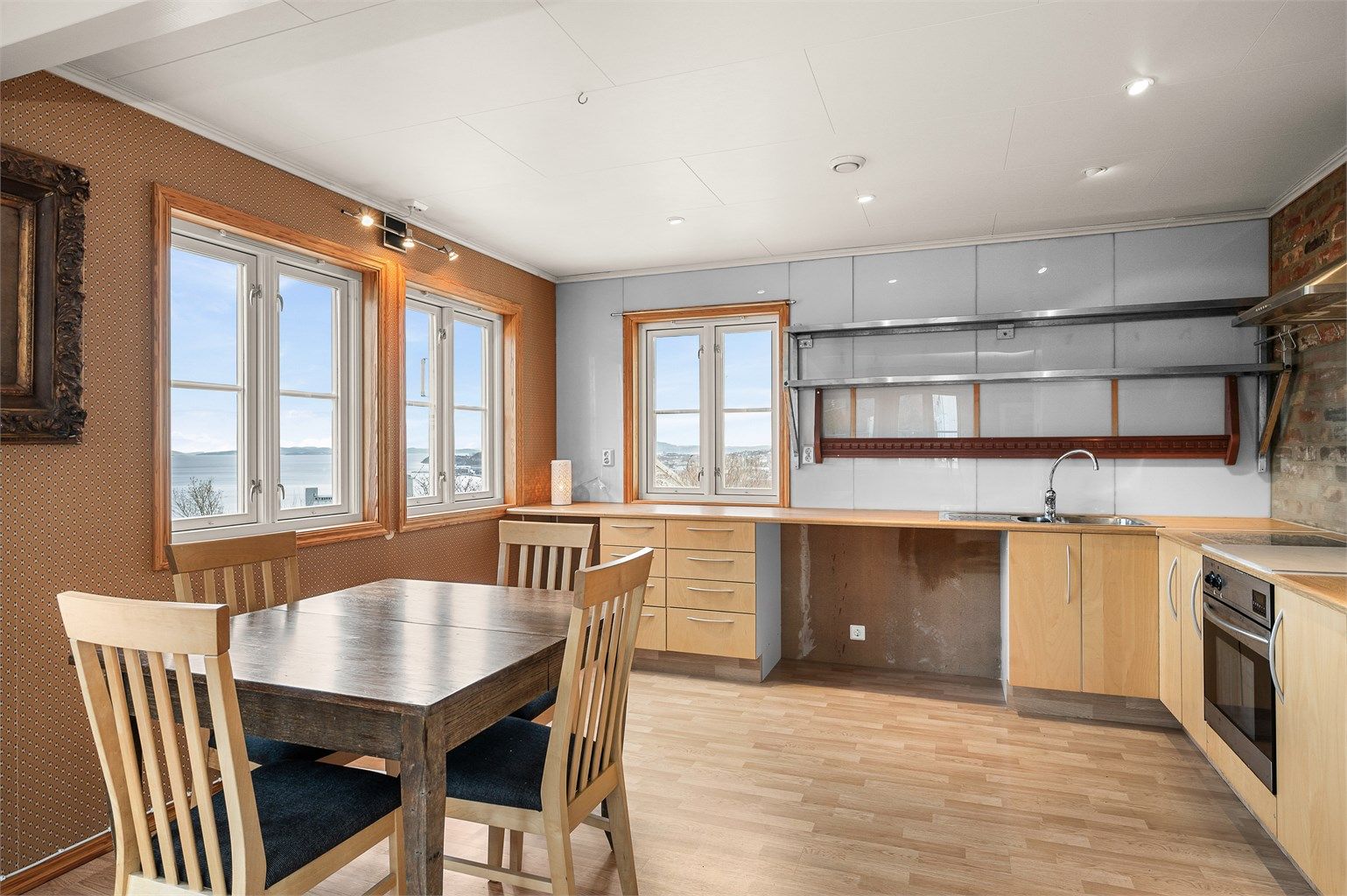 Romslig kjøkken med god plass til spisebord ved vinduene, slik at både måltider og hverdagsøyeblikk kan nytes med utsikt mot omgivelsene.