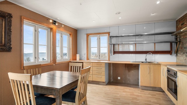 Romslig kjøkken med god plass til spisebord ved vinduene, slik at både måltider og hverdagsøyeblikk kan nytes med utsikt mot omgivelsene.