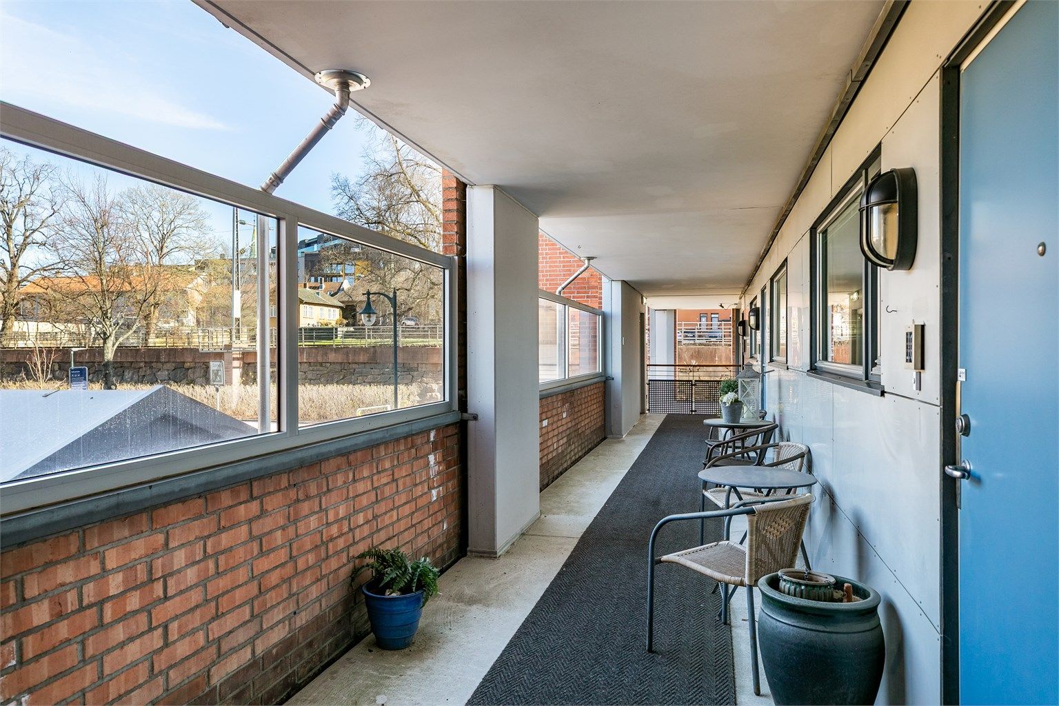 Svalgangen er godt skjermet fra vær og vind. Dette er fellesareal, men av flere seksjonseiere pent møblert med blant annet små sittegrupper.