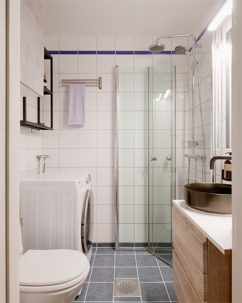 Videre har badet gulvstående toalett og dusjhjørne med glassdører og to-greps armatur samt regnfalldusj. Det er opplegg for vaskemaskin. 