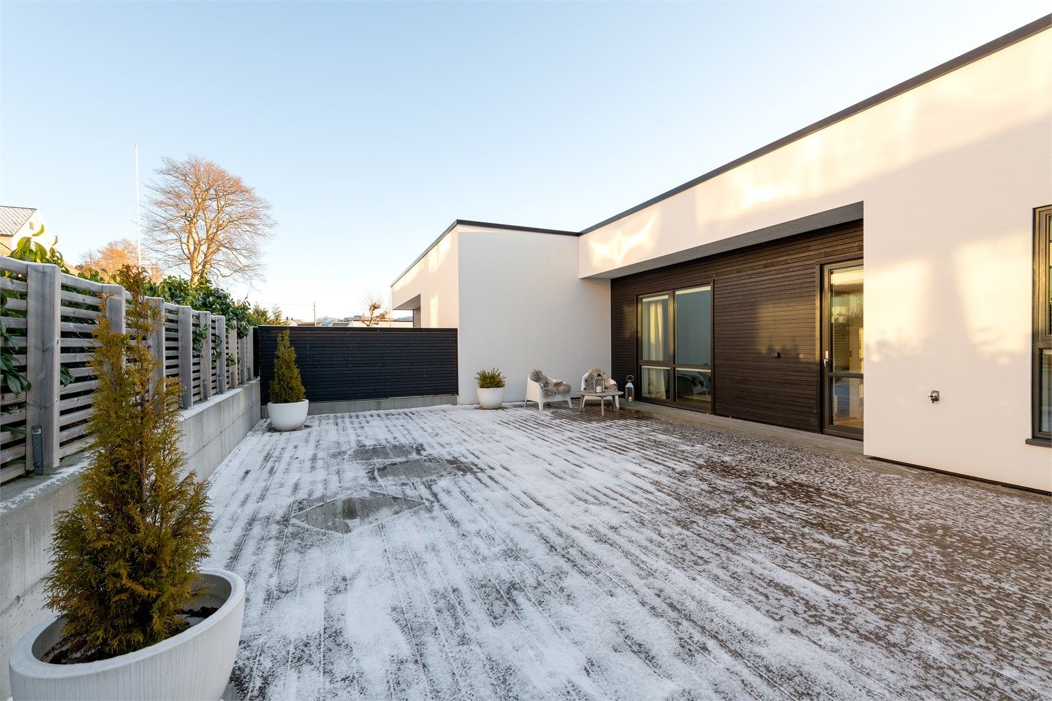 Stor markterrasse/uteplass mot nord med adkomst fra gang i hovedetasjen. Levegg mot naboer