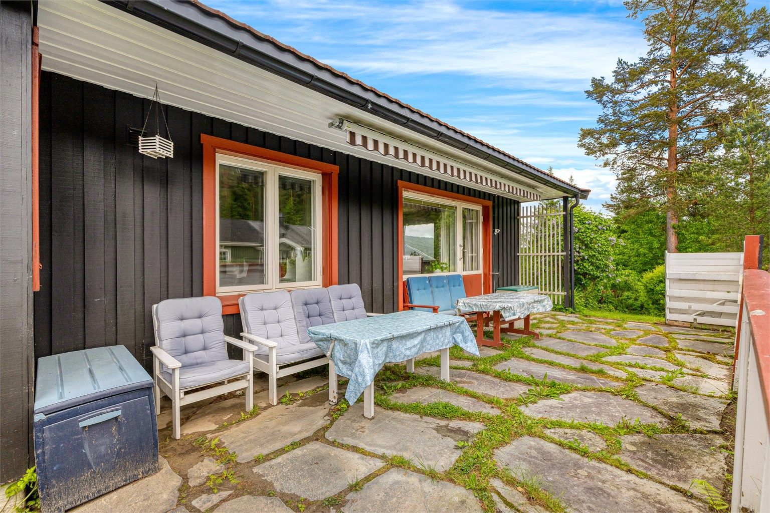 Hyggelig markterrasse med utgang fra boligens stue, terrassemarkise montert for praktisk solskjerming på solfylte varme dager