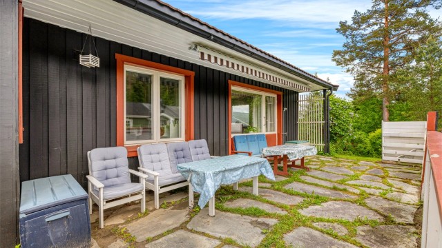 Hyggelig markterrasse med utgang fra boligens stue, terrassemarkise montert for praktisk solskjerming på solfylte varme dager