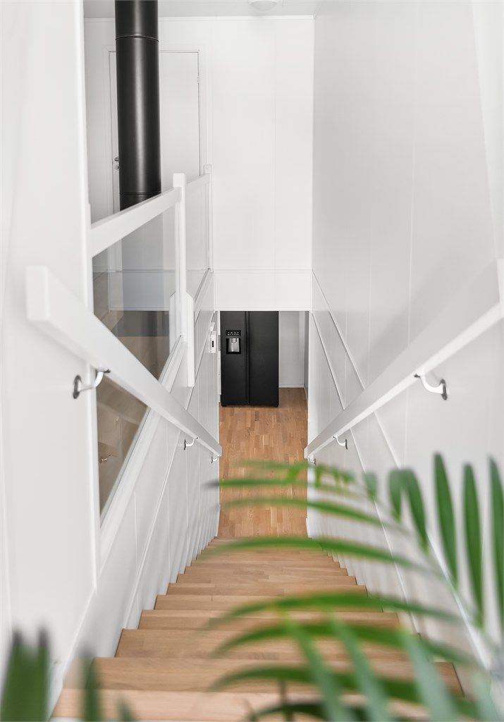 Innvendig trapp i tre med rekkverk av glassfelter binder etasjene elegant sammen.