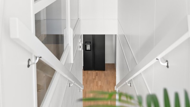 Innvendig trapp i tre med rekkverk av glassfelter binder etasjene elegant sammen.