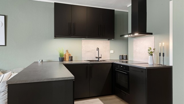 Kjøkkeninnredning fra 2019 med sorte glatte fronter og benkeplate av laminat. Integrert stekeovn, platetopp, oppvaskmaskin og kjøleskap med fryser. Vegghengt ventilator.