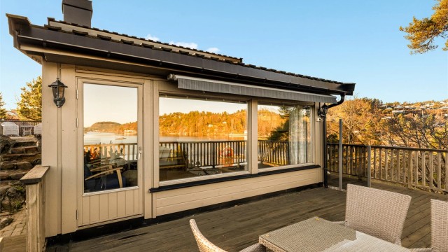 Store vindusflater i stua speiler utsikten en vakker høstdag.