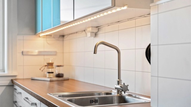 Kjøkkenet har glatte fronter, benkeplate med laminert overflate og laminerte plater over benken