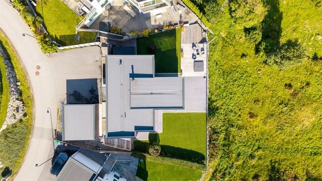 Oversikt over tomtens utnyttelse med gårdsplass, garasje, plen og terrasser.