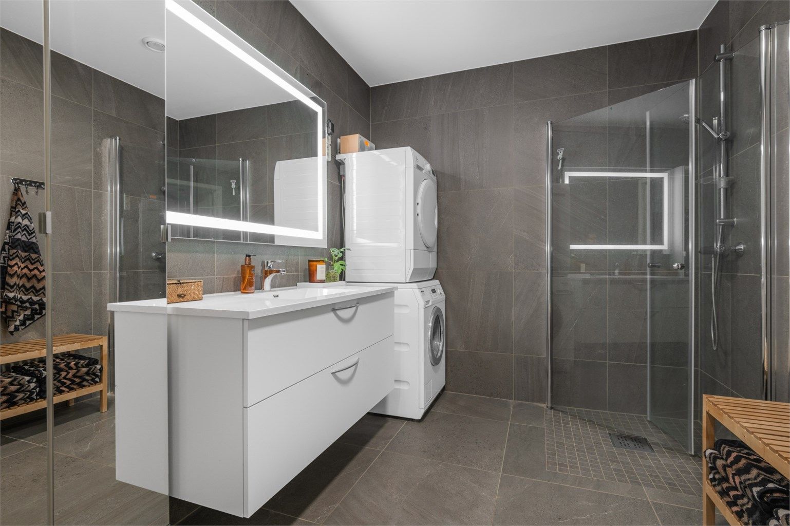 Videre er badet innredet med servantskap med speil og lys, sideskap og dusjhjørne. 