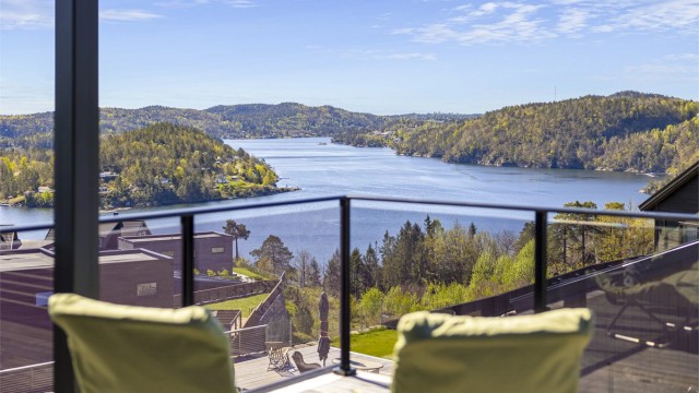 Det er en magisk utsikt til Tvedestrandsfjorden fra flere steder på eiendommen. Glassrekkverk som rammer inn utsikten.