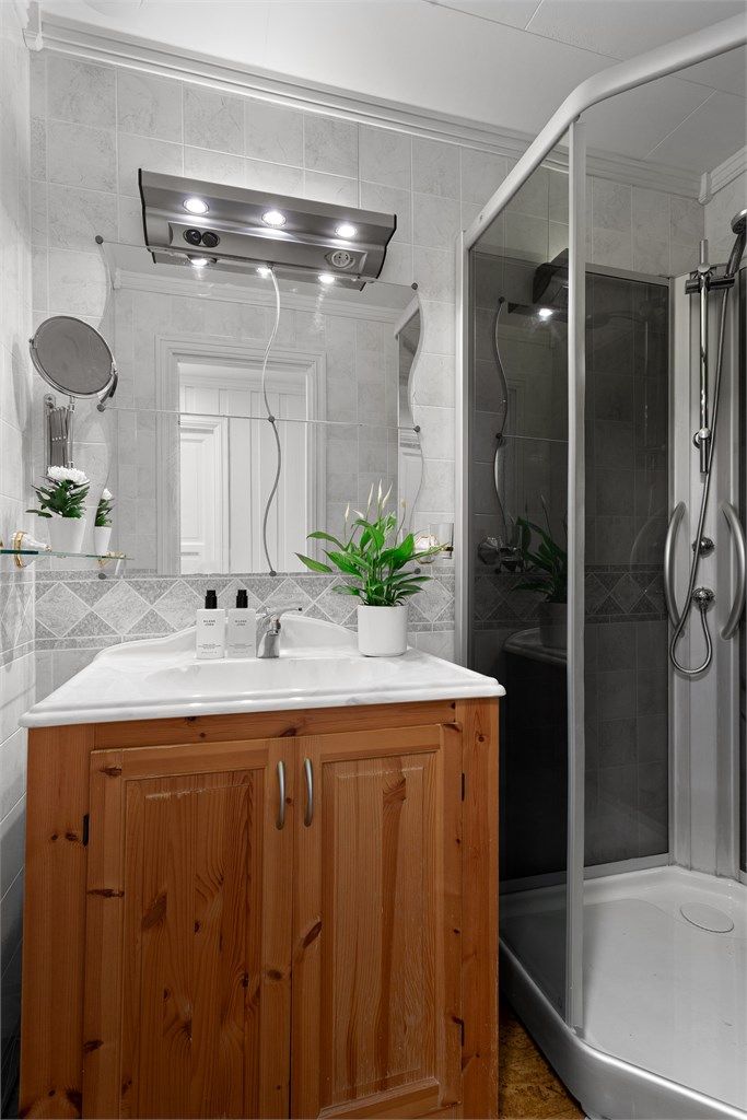 Bad 2 med belegg på gulv og veggflater med våtromsplater. Innredet med gulvstående servantskap med profilerte fronter og ovenpåliggende servant.