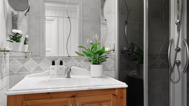 Bad 2 med belegg på gulv og veggflater med våtromsplater. Innredet med gulvstående servantskap med profilerte fronter og ovenpåliggende servant.