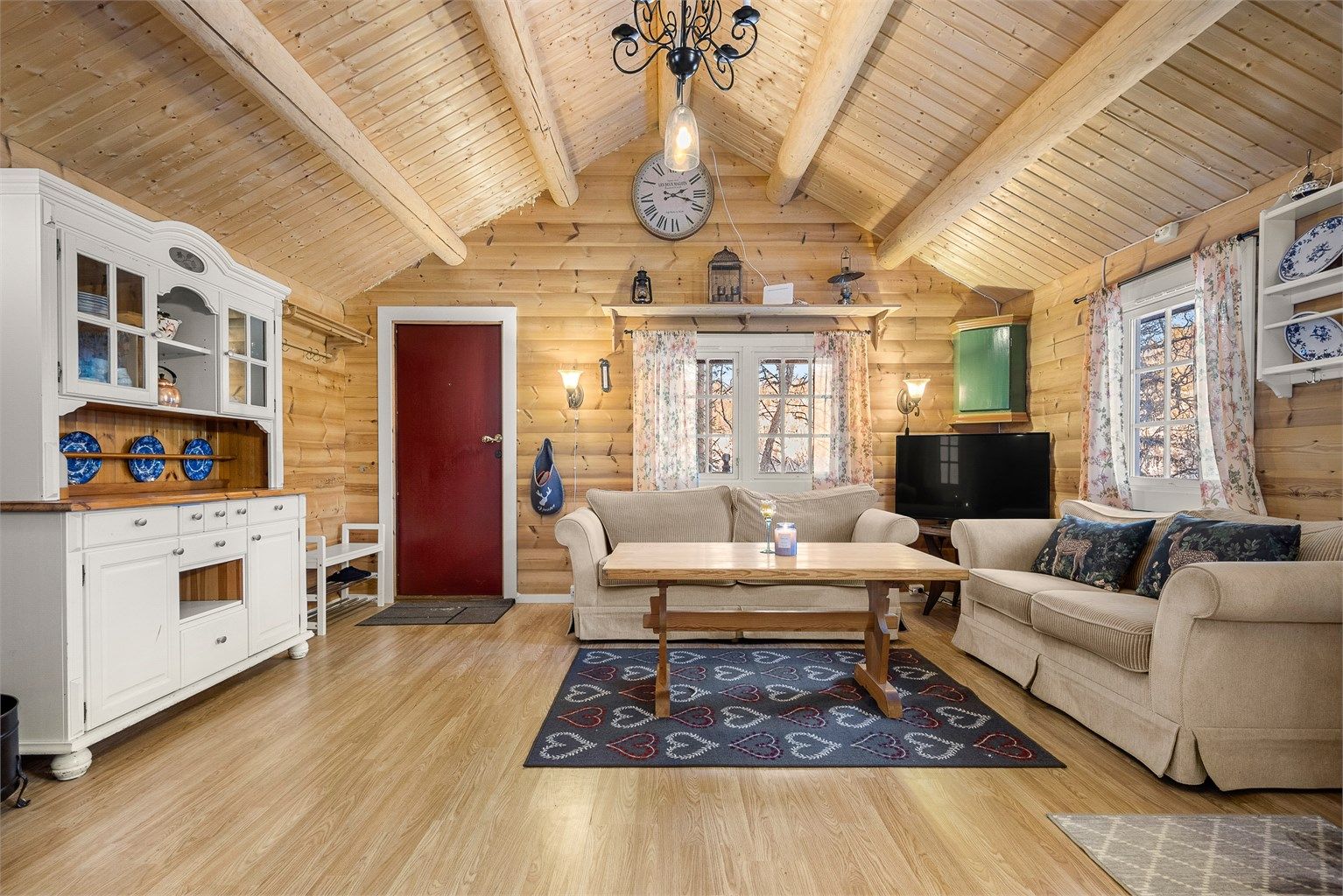 Lun og stemningsfull stue med synlige tømmervegger og peisovn som skaper varme og hyttekos året rundt.