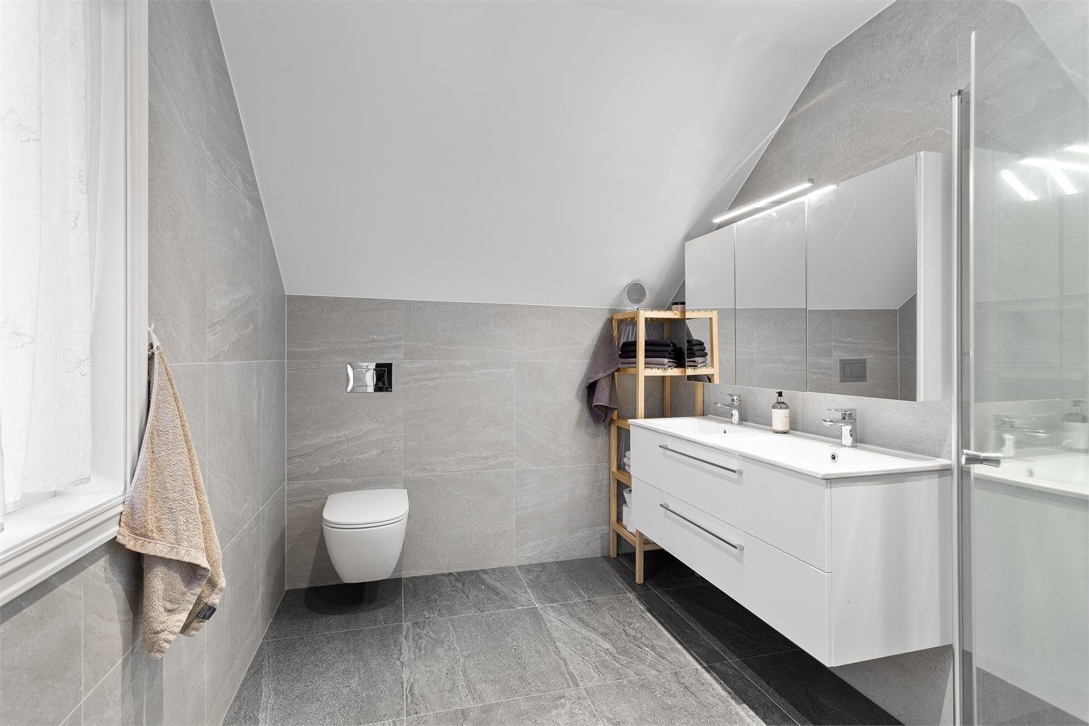 Flott flislagt bad 2 fra 2023 med adkomst fra hovedsoverommet. Downlights i himlingen. Innredet med vegghengt servantinnredning med skuffer. Speilskap med overlys over servant.