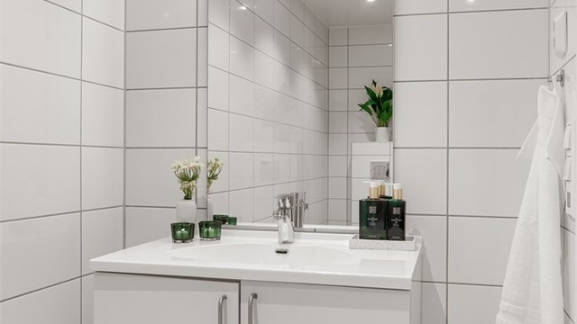 Dusjbad/wc - Hvit glatt innredning med helstøpt servant med underskap. Speil med belysning og stikkontakt.