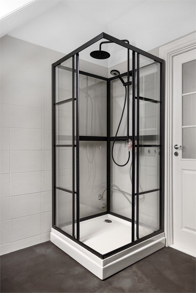 Dusjkabinett med sorte profiler som matcher de øvrige detaljene på badet.