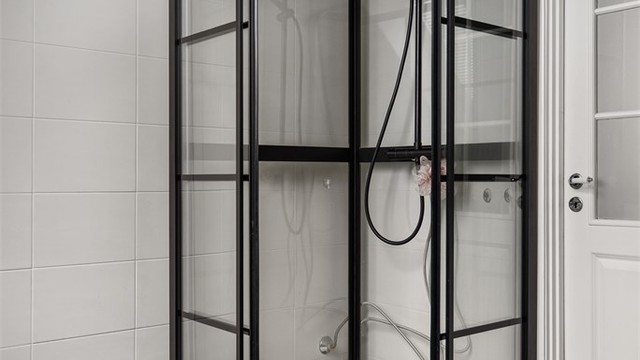 Dusjkabinett med sorte profiler som matcher de øvrige detaljene på badet.