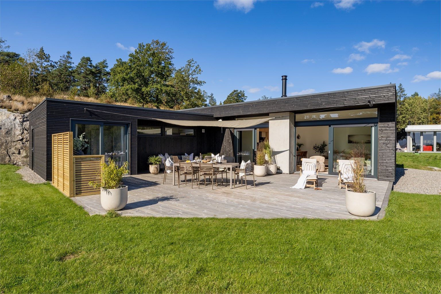 Arkitekttegnet funkis-hytte i L-form, designet for å omfavne uterommet og sjøutsikten.