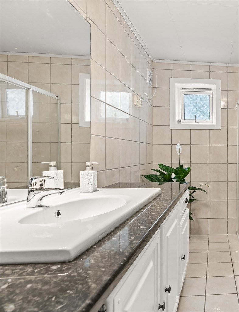 Badet har vegghengt servant med ovenpåliggende servant og ett-greps armatur. Her er det også opplegg for vaskemaskin.