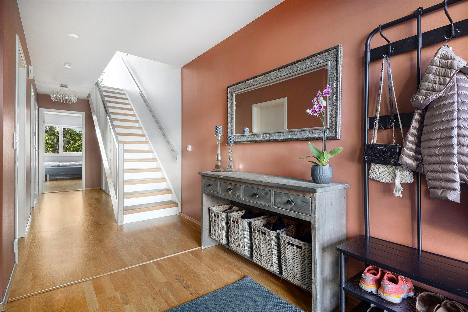 Velkommen inn i en lys og romslig entré. Rikelig med plass til klesoppheng, hyller og plassbygd skap under trapp opp til 2. etasje 