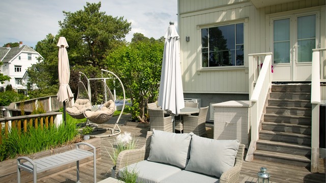 Fra stuen er det utgang til en stor terrasse belagt med terrassebord, med trapp ned til hagen.