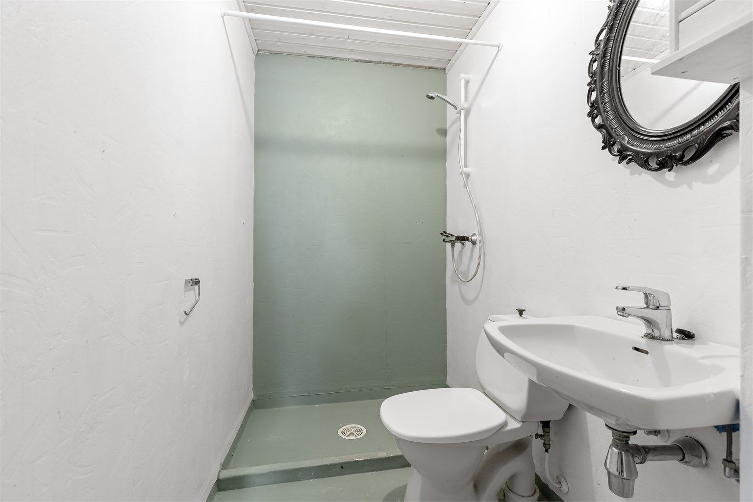 Badet i underetasjen er fra byggeåret og inneholder toalett, servant og dusjnisje.
