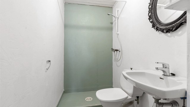 Badet i underetasjen er fra byggeåret og inneholder toalett, servant og dusjnisje.