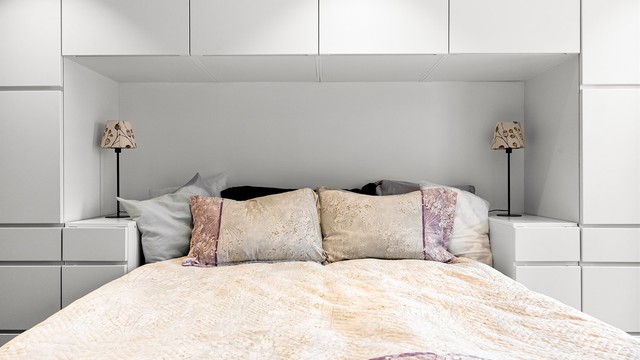 Sengen er elegant innrammet av en stor garderobeløsning som gir rikelig med oppbevaringsplass og samtidig utnytter rommet svært godt.