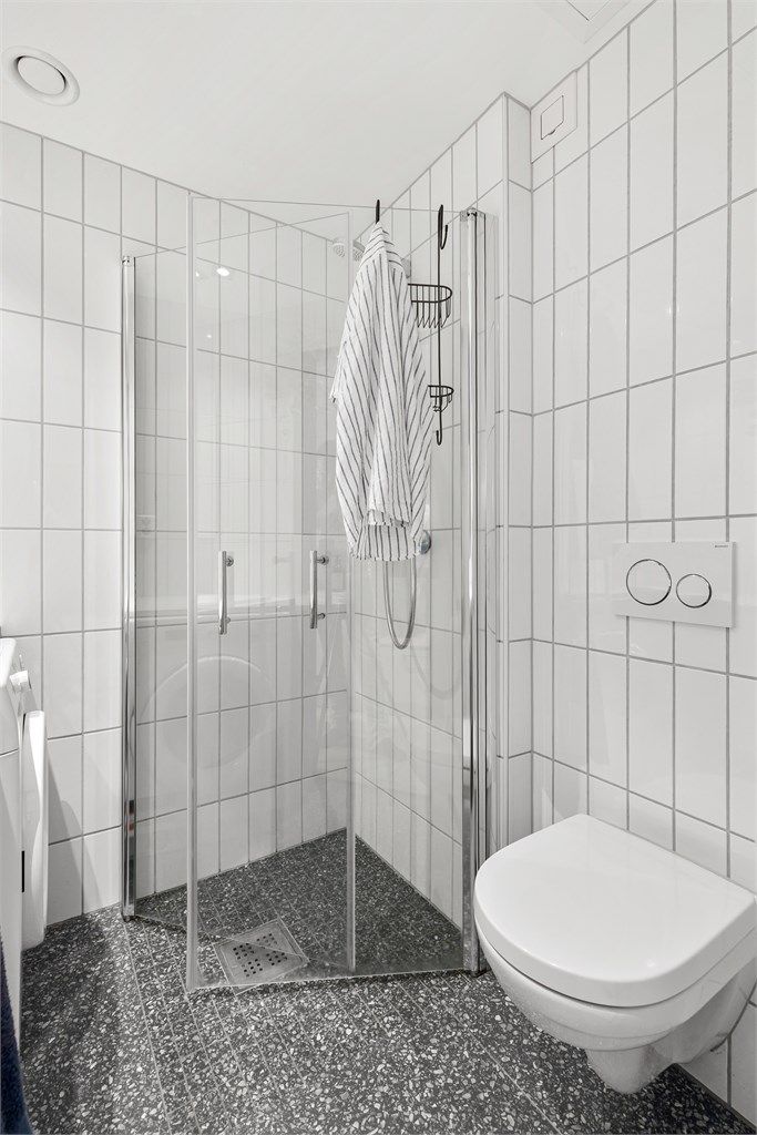 Baderommet er innredet med vegghengt servant, speilskap, dusjhjørne, vegghengt toalett og opplegg for vaskemaskin.