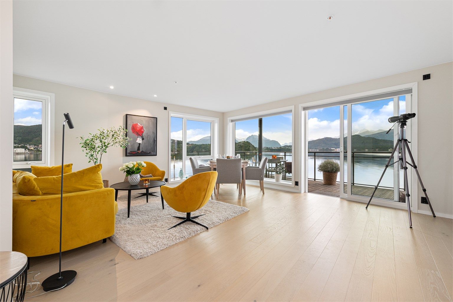 Lys og romslig stue med store vindusflater og en fantastisk utsikt mot fjord og fjell - Foto: Stian Wiik