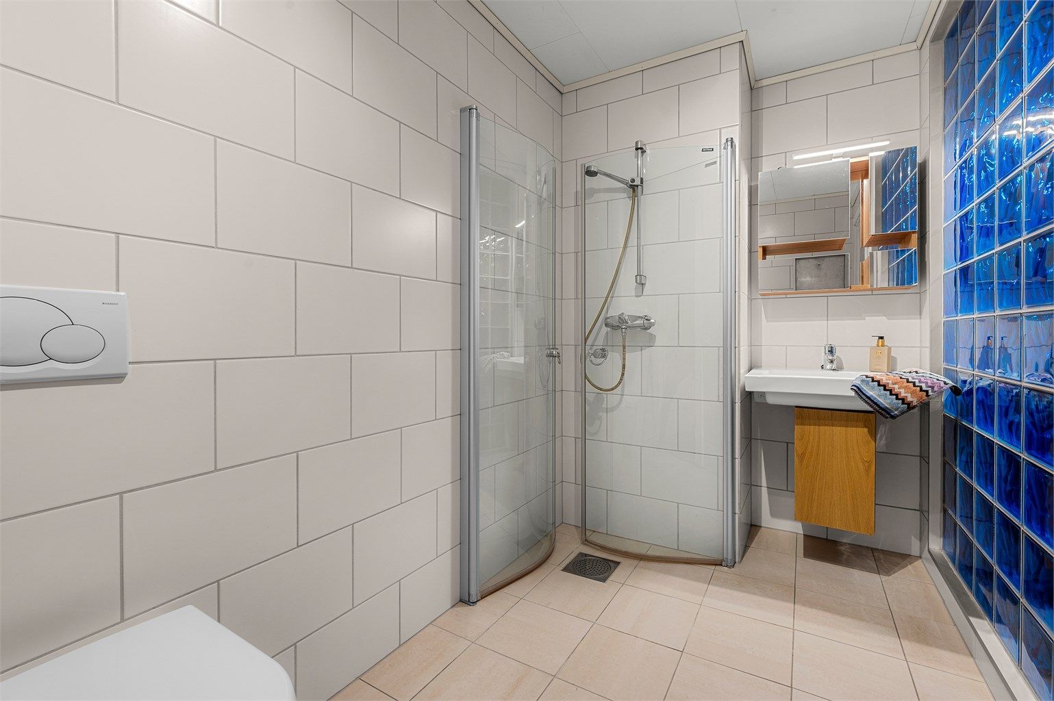 Bad i underetasjen på 4,5 kvm med flislagte overflater, gulvvarme og praktisk planløsning.