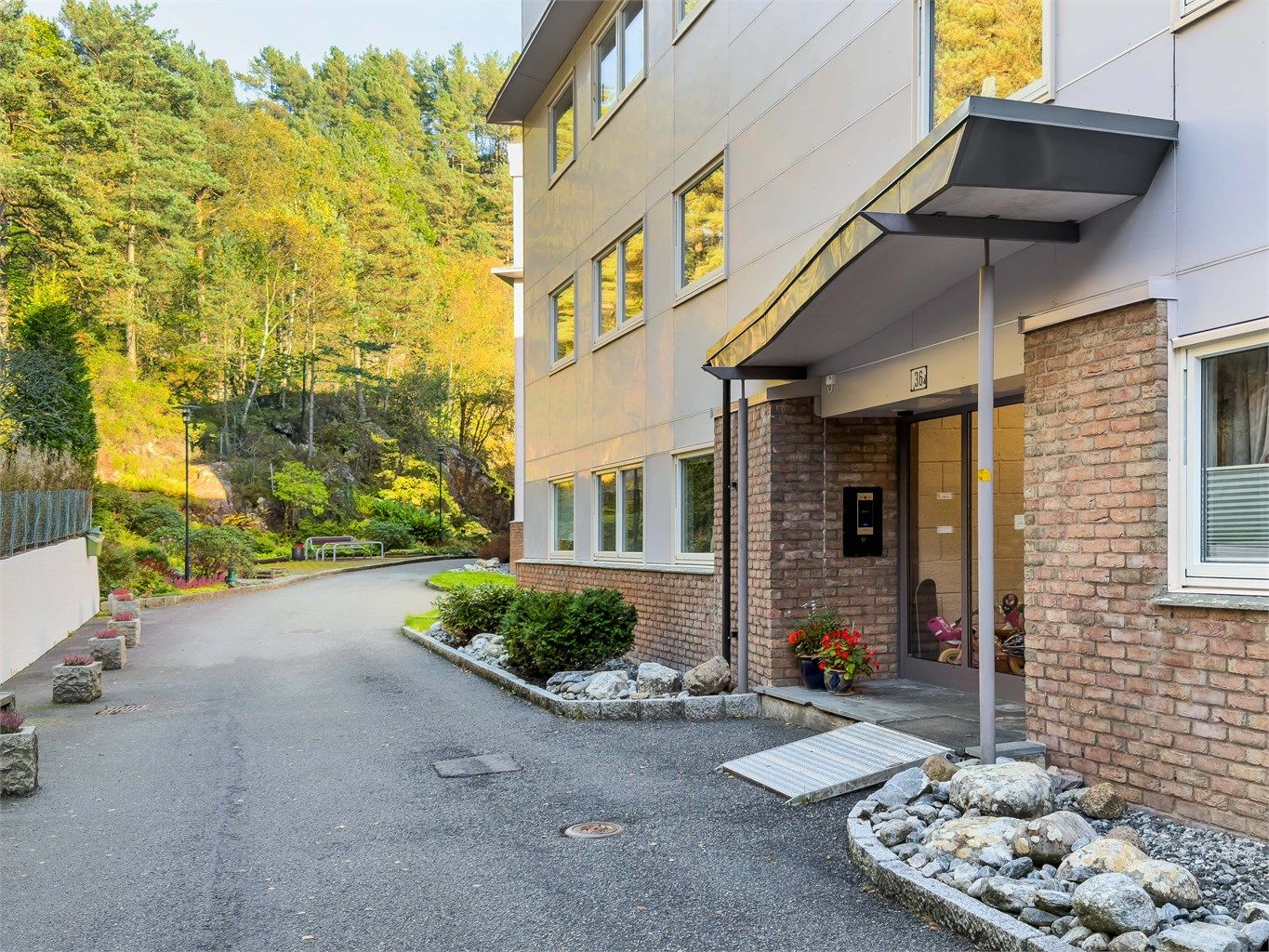 - Velholdt inngangsparti ved Barliveien 36 med asfaltert adkomst og pene beplantninger -