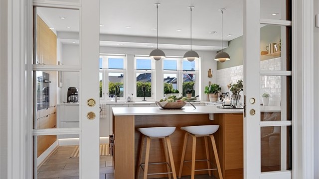 Dobbel skyvedør med glassfront skiller kjøkken og tv stue.