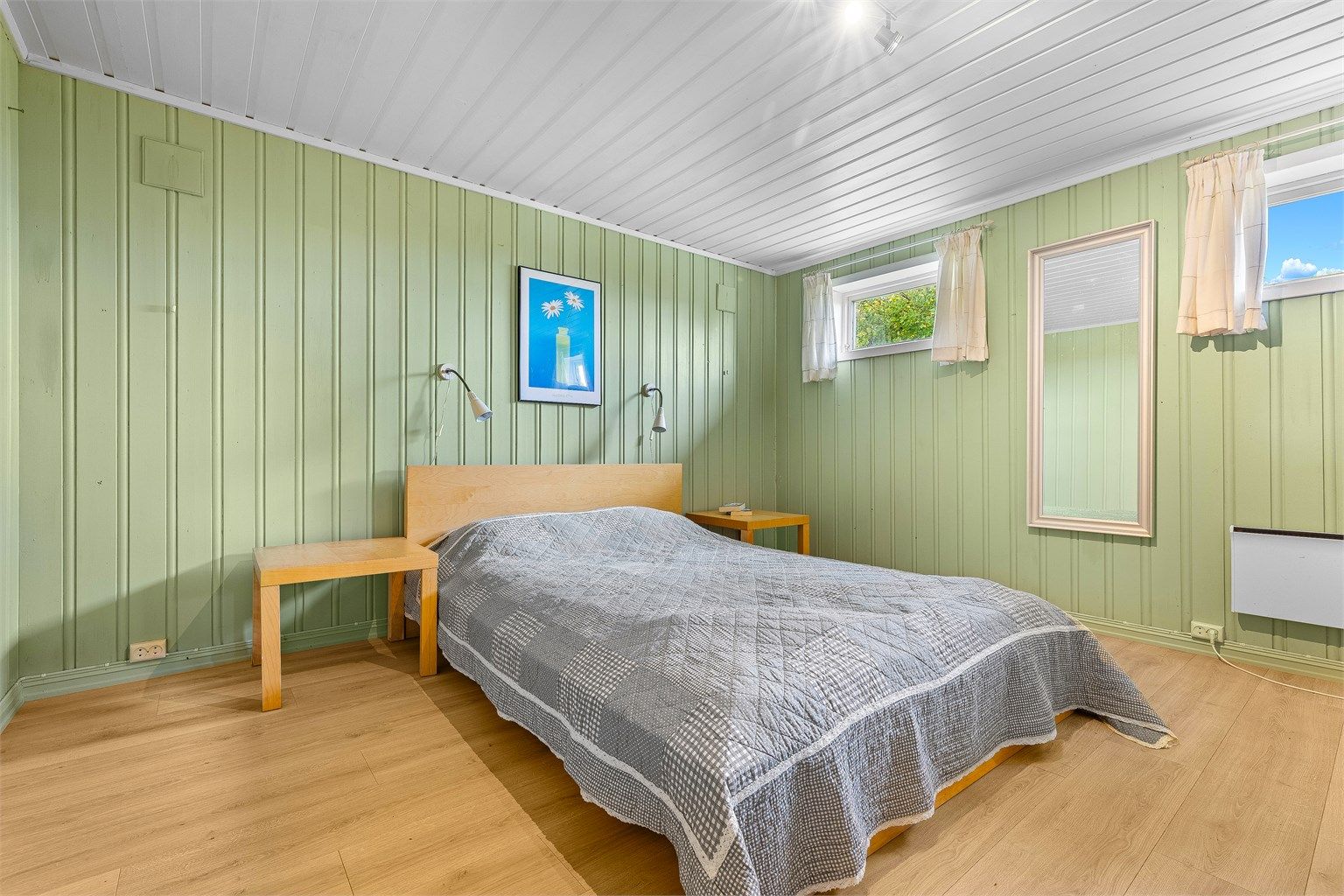 Innredet rom i kjelleretasjen med panelte overflater og plass til seng.