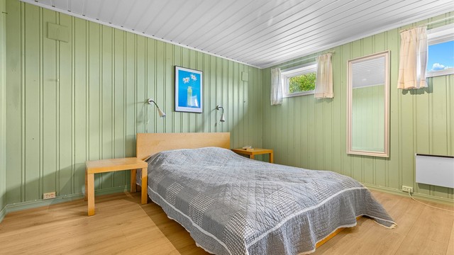Innredet rom i kjelleretasjen med panelte overflater og plass til seng.