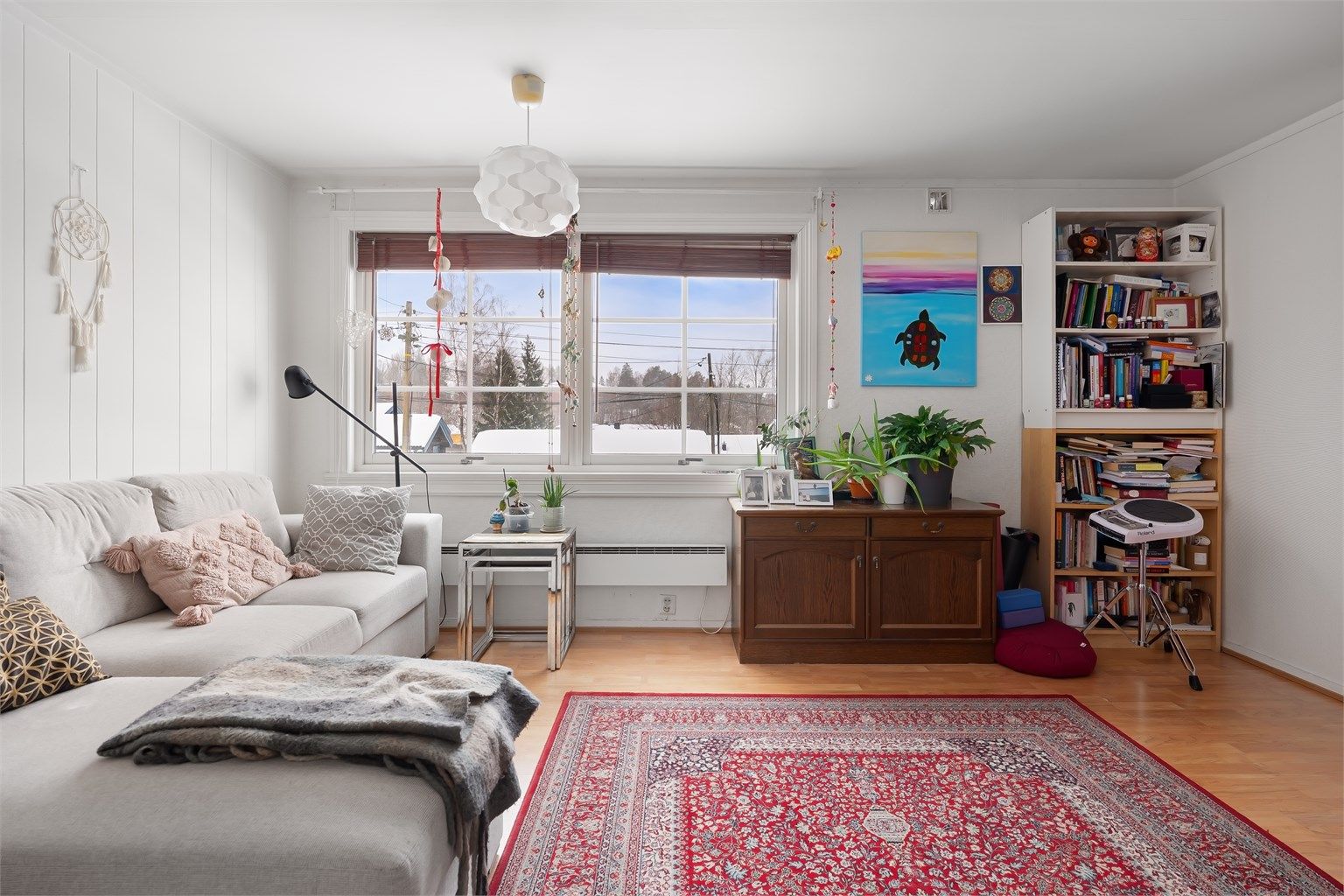 Stuen i sokkelleiligheten har laminat på gulvet og plass til en sofagruppe.