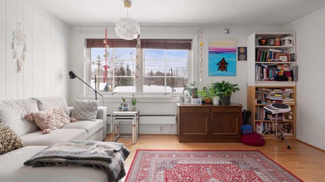 Stuen i sokkelleiligheten har laminat på gulvet og plass til en sofagruppe.