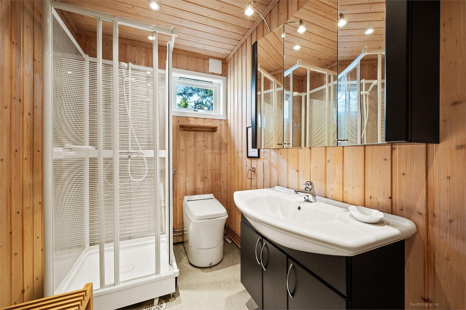 Baderommet er innredet med dusjkabinett, servantskap og et forbrenningstoalett (Cinderella Classic).