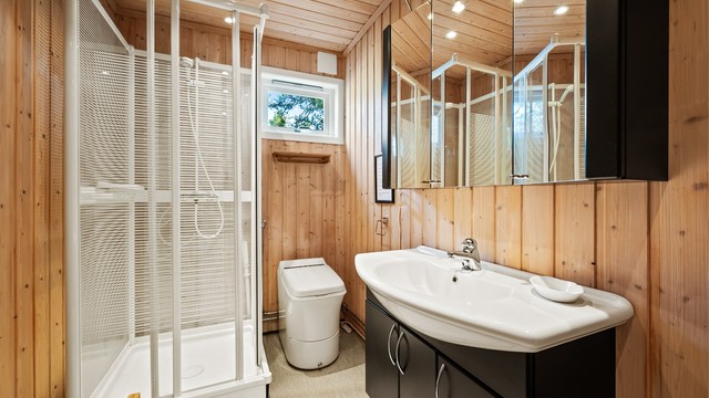 Baderommet er innredet med dusjkabinett, servantskap og et forbrenningstoalett (Cinderella Classic).