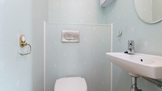 Toalettrom i første etasje innredet med vegghengt toalett og servant.